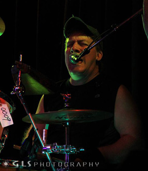 A man singing while playing the drums